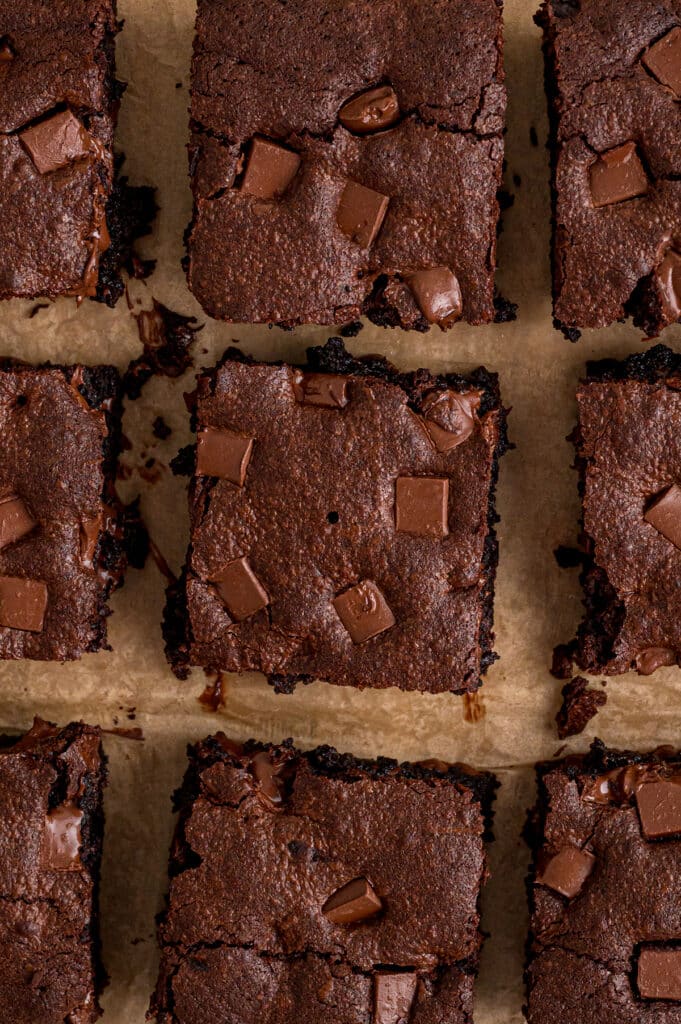 Overhead view of neatly sliced chocolate chunk brownies on parchment paper.