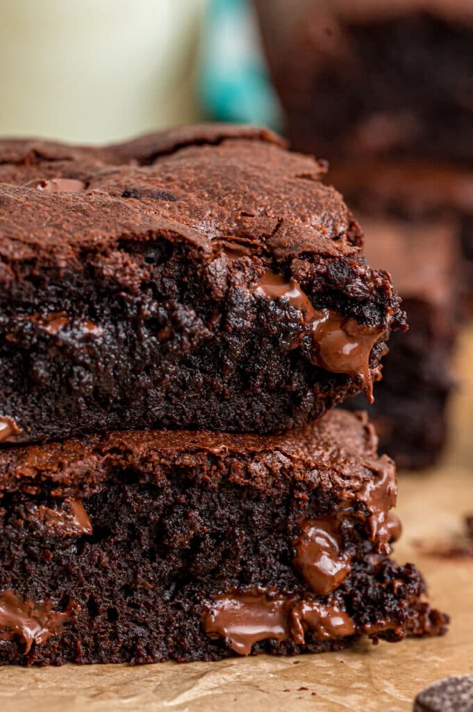 Close-up of gooey chocolate brownies stacked on a wooden surface.