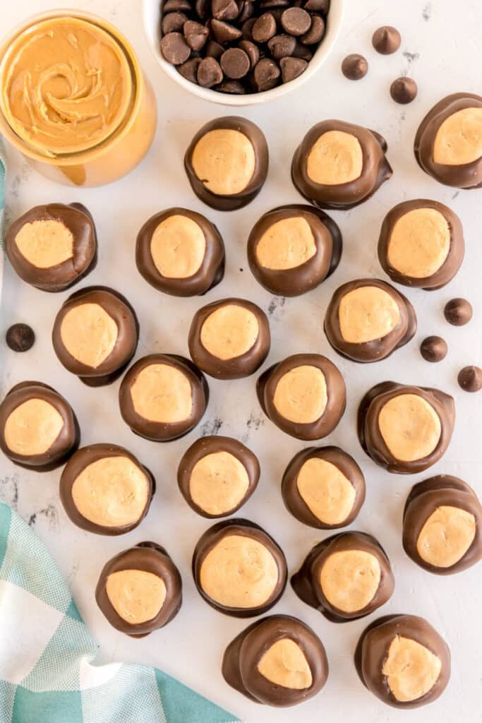 Scattered buckeye balls with jars of chocolate chips and peanut butter.