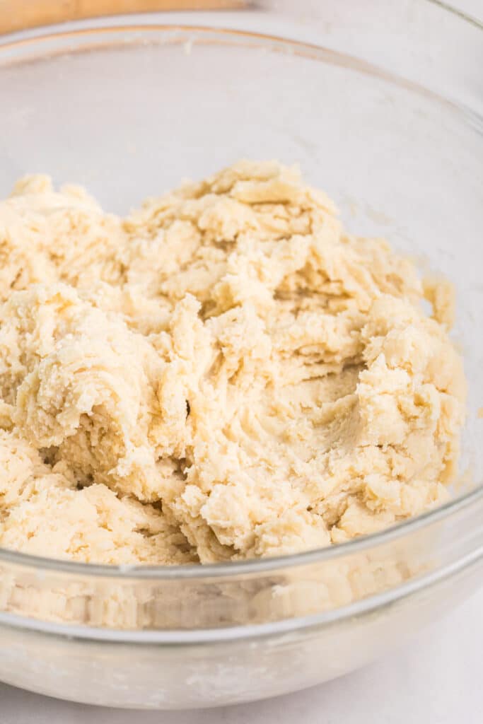 Raw pie dough in a glass mixing bowl.