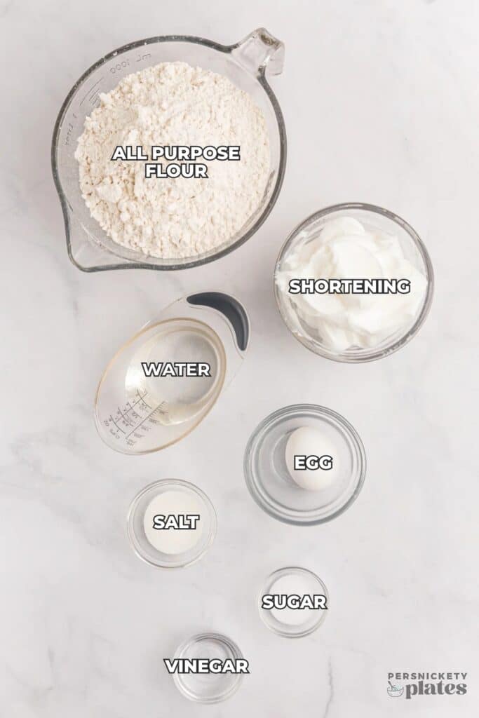 Flat lay of labeled pie crust ingredients in glass bowls.