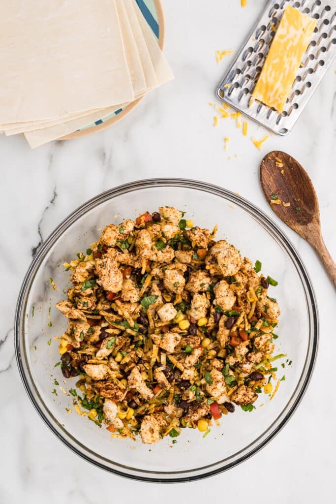 Southwest egg roll filling in a glass bowl with a spoon nearby.