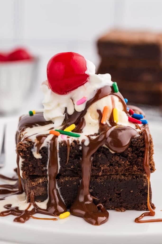 Brownie sundae topped with ice cream, whipped cream, chocolate sauce, sprinkles, and a cherry.