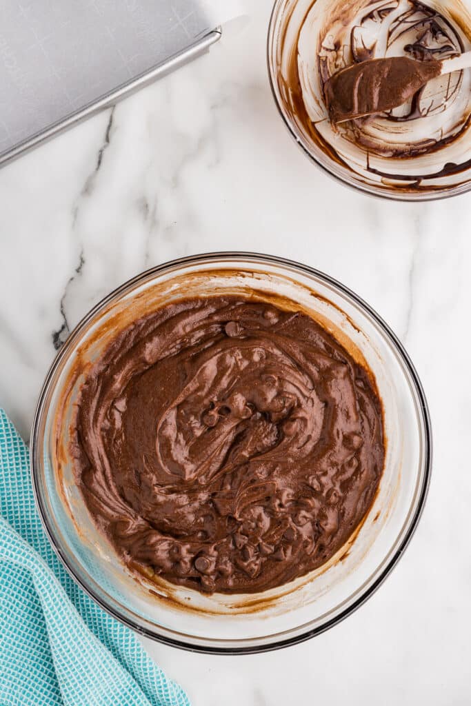 Glass mixing bowl filled with thick chocolate brownie batter.