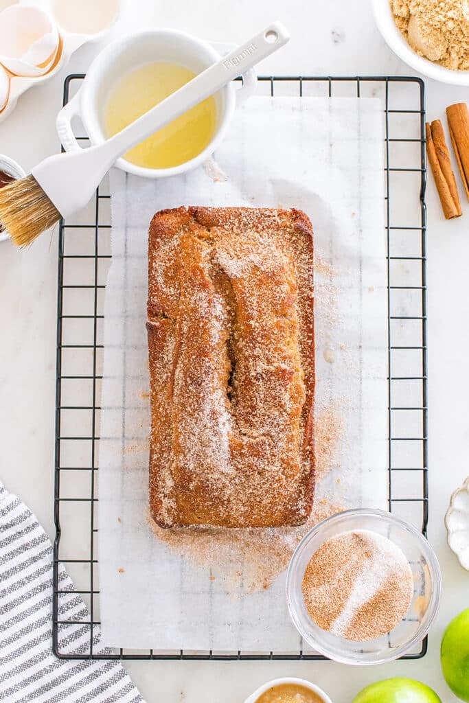 Apple cider donut bread on rack with melted butter and cinnamon-sugar for topping.