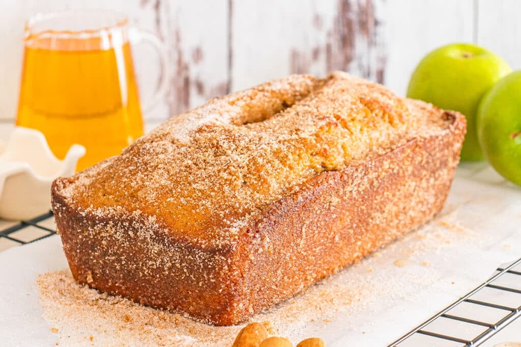 Cinnamon-sugar apple cider donut bread loaf on cooling rack.