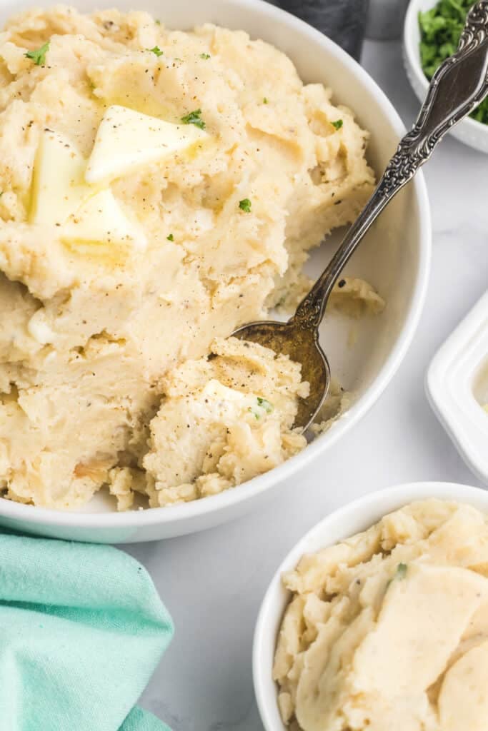 Bowl of mashed potatoes with melted butter and a spoon.