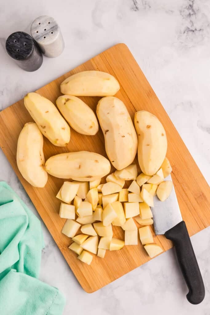 Peeled and chopped potatoes on a cutting board.