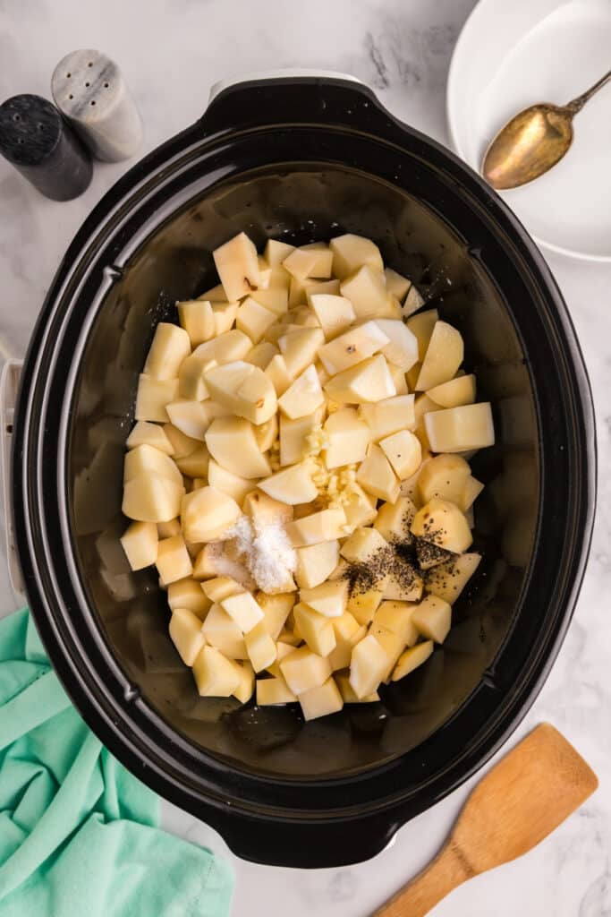 Cubed potatoes with seasoning in a slow cooker.