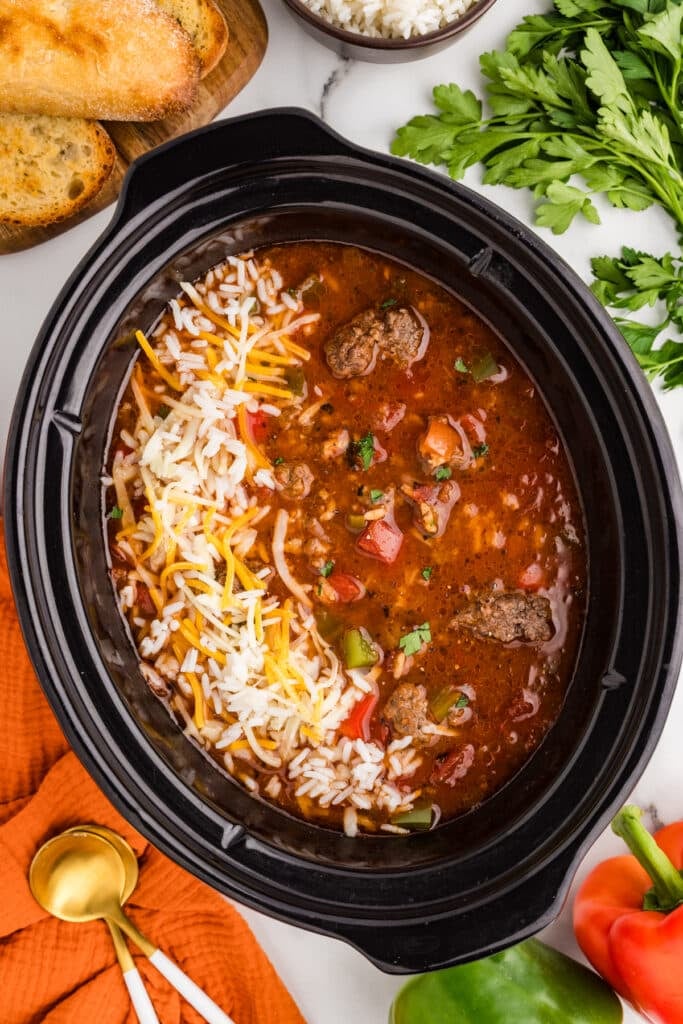 Slow cooker stuffed pepper soup topped with cheese and rice.