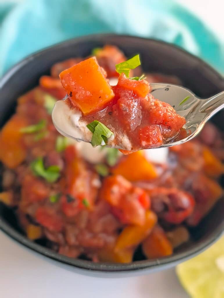 A spoonful of chili lifted above a bowl.