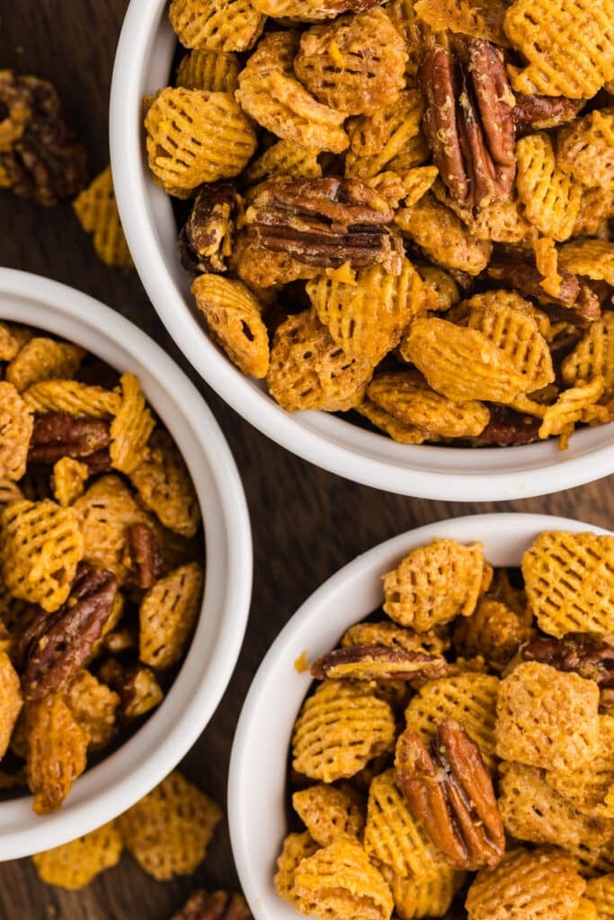 Butter pecan snack mix served in small white bowls on a wooden surface.