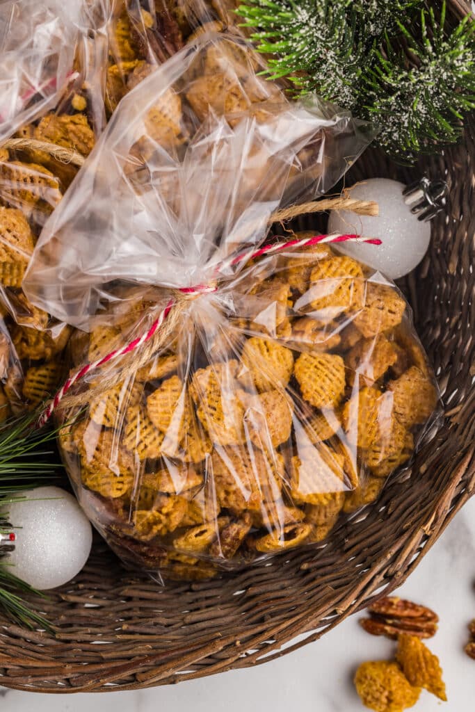 Clear gift bags filled with golden butter pecan snack mix tied with twine and red string.