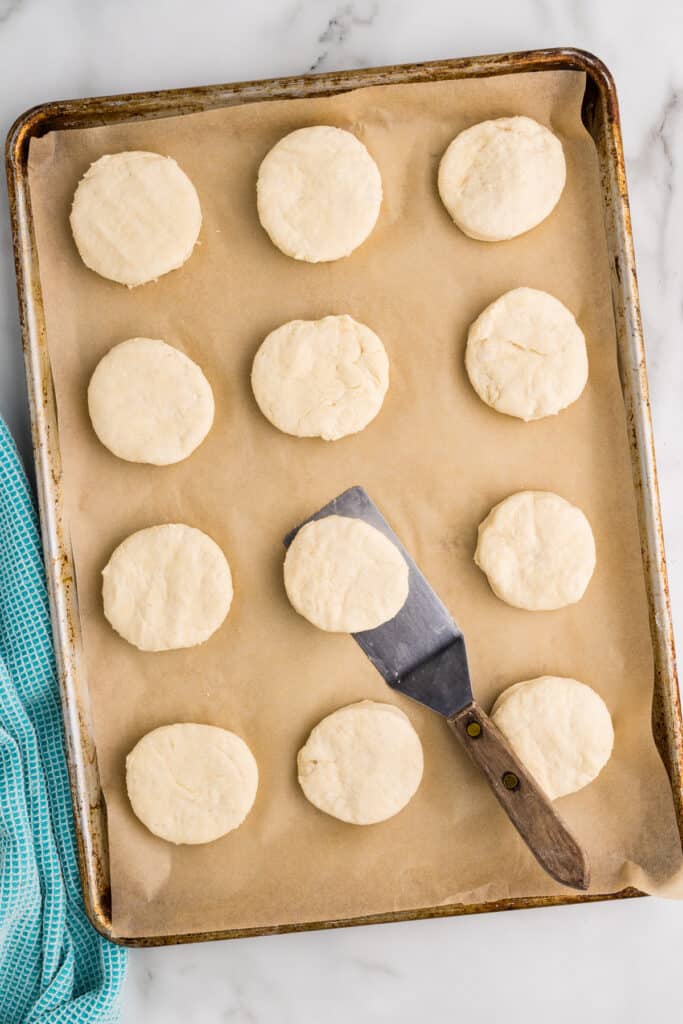 Unbaked biscuits arranged on a parchment-lined baking sheet.