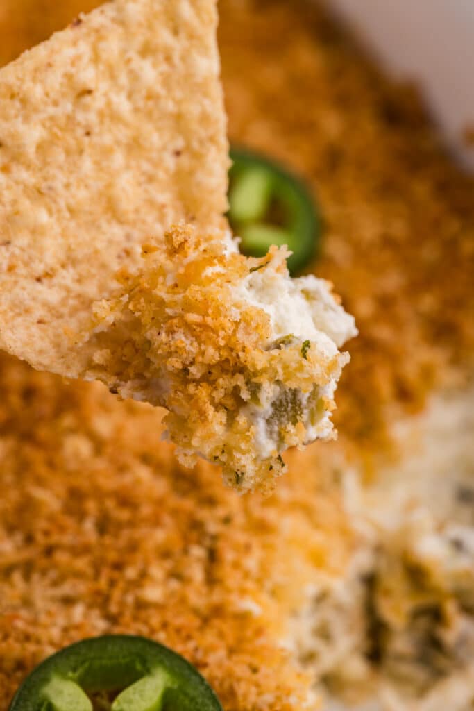 Cracker dipped into jalapeño popper dip with a crispy breadcrumb topping.