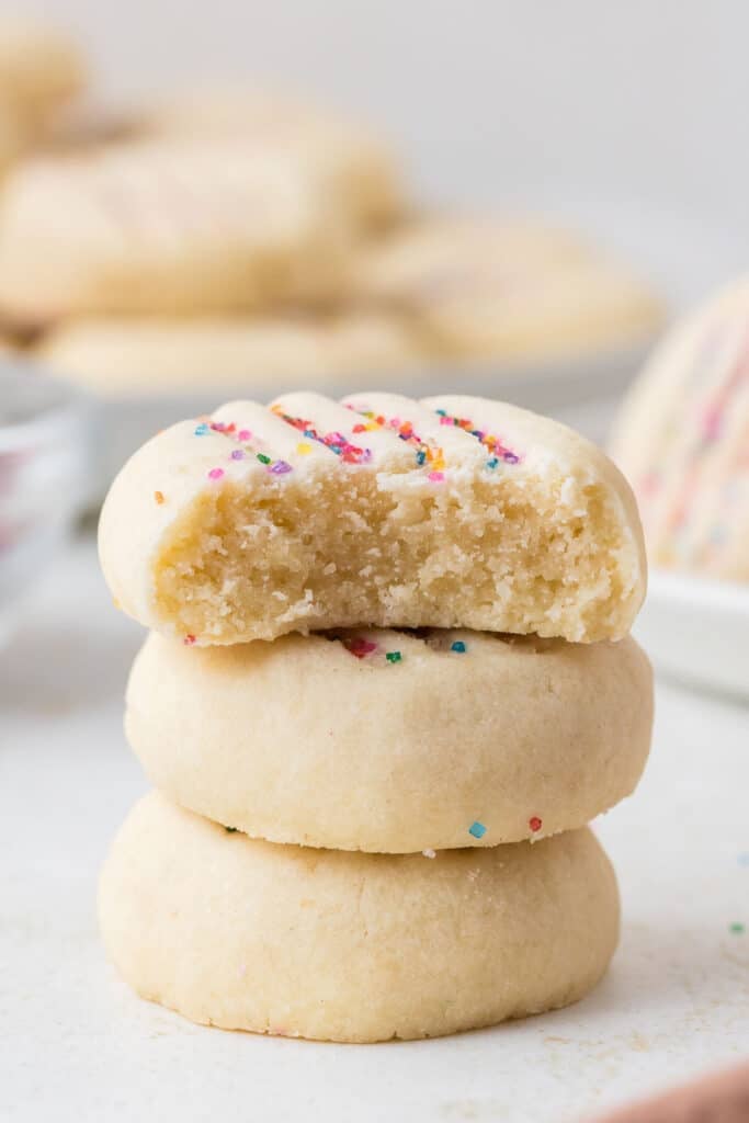Stack of shortbread cookies with one cookie bitten to show the inside.