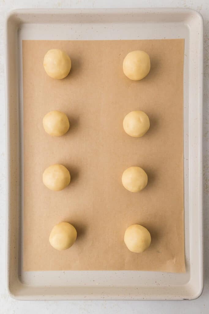 Evenly spaced balls of cookie dough on a parchment-lined baking sheet.