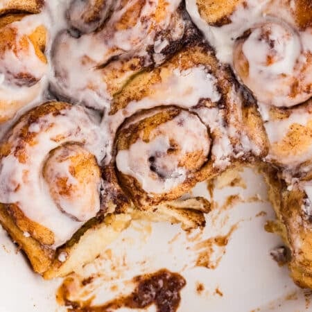 Baking dish of cinnamon rolls with one roll removed.