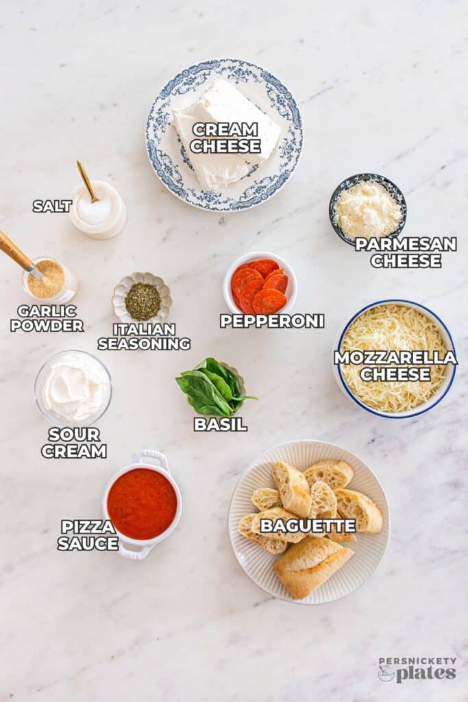 Labeled ingredients for slow cooker pizza dip arranged on a marble surface.