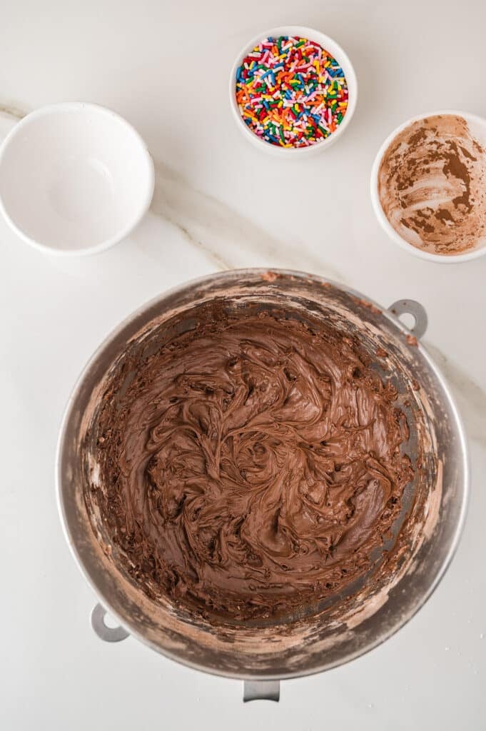Chocolate frosting swirled in a metal mixing bowl.